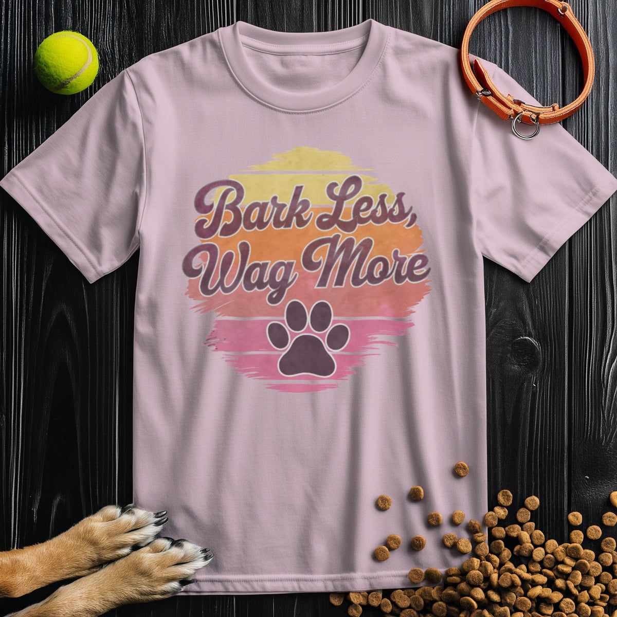 Light pink Bark Less, Wag More T-Shirt with paw print and sunset design. Soft cotton unisex shirt perfect for dog lovers.