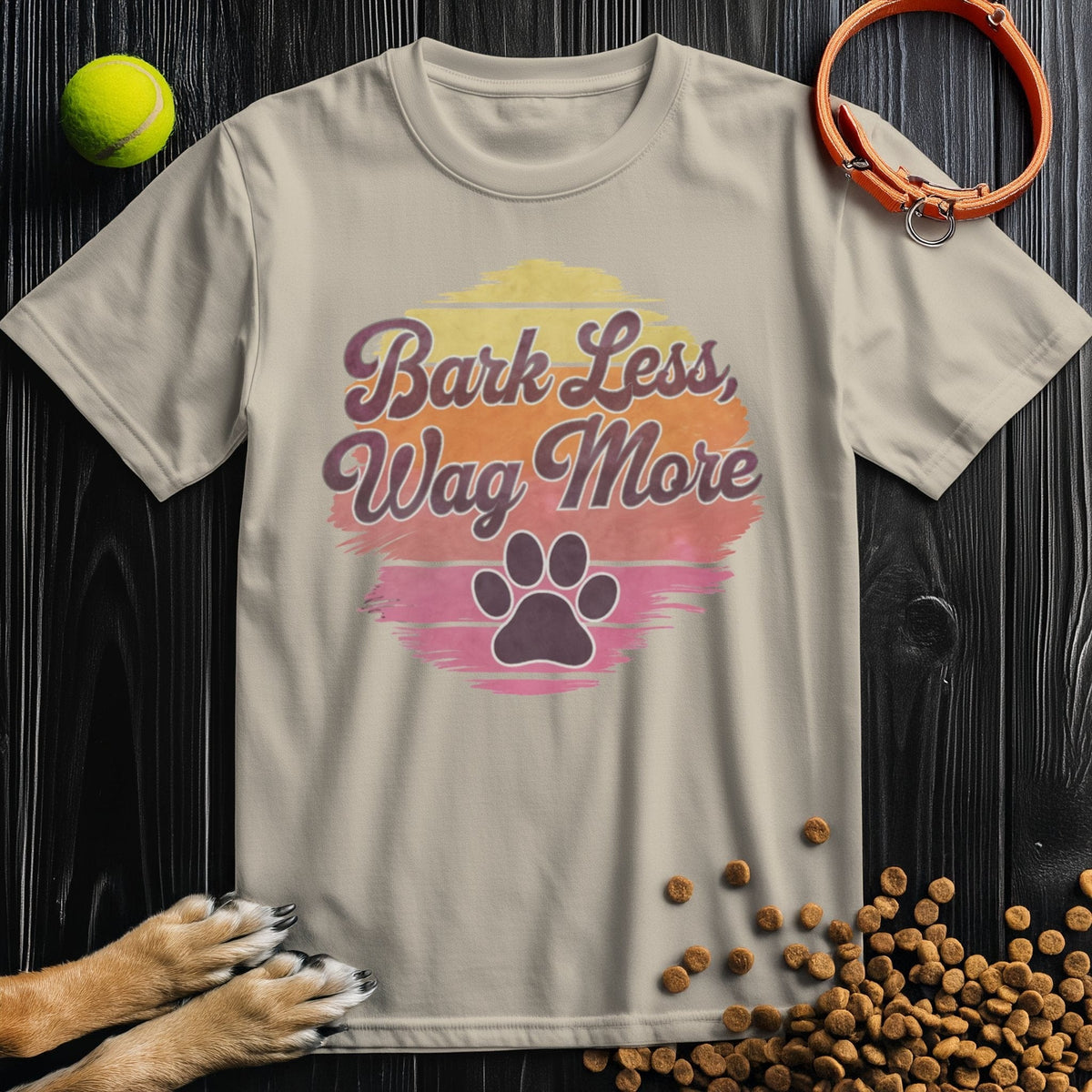 Beige Bark Less, Wag More T-Shirt featuring a retro paw print graphic. 100% cotton, unisex fit for dog lovers and casual outfits.