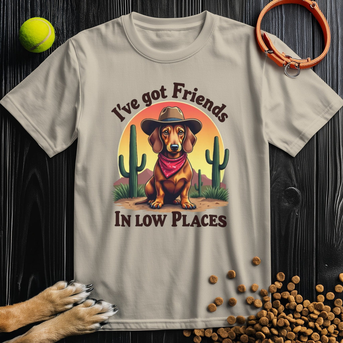Beige 'I've Got Friends In Low Places T-Shirt' featuring a cowboy dachshund illustration, perfect for pet lovers and summer style.
