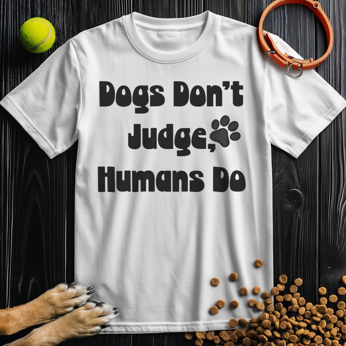 White cotton 'Dogs Don't Judge, Humans Do' t-shirt with bold black text and paw print, ideal for dog lovers seeking comfort and style.